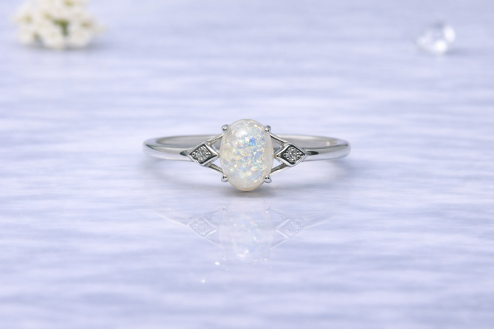 Silver ring with a large central gemstone on a light blue textured background